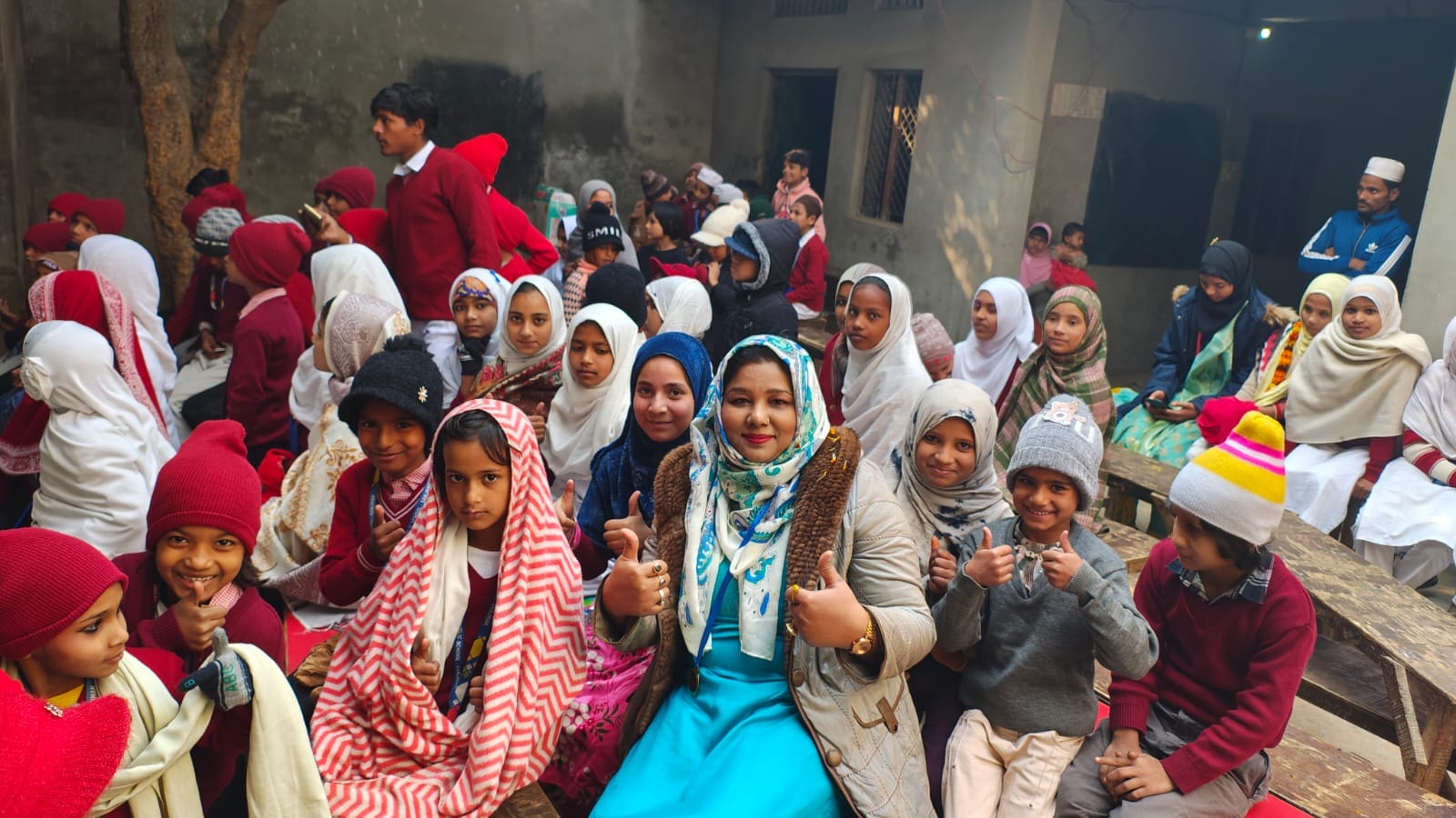 Advocate Shahjabeen Qazi giving thumbs up seated right with the school children in Tawli