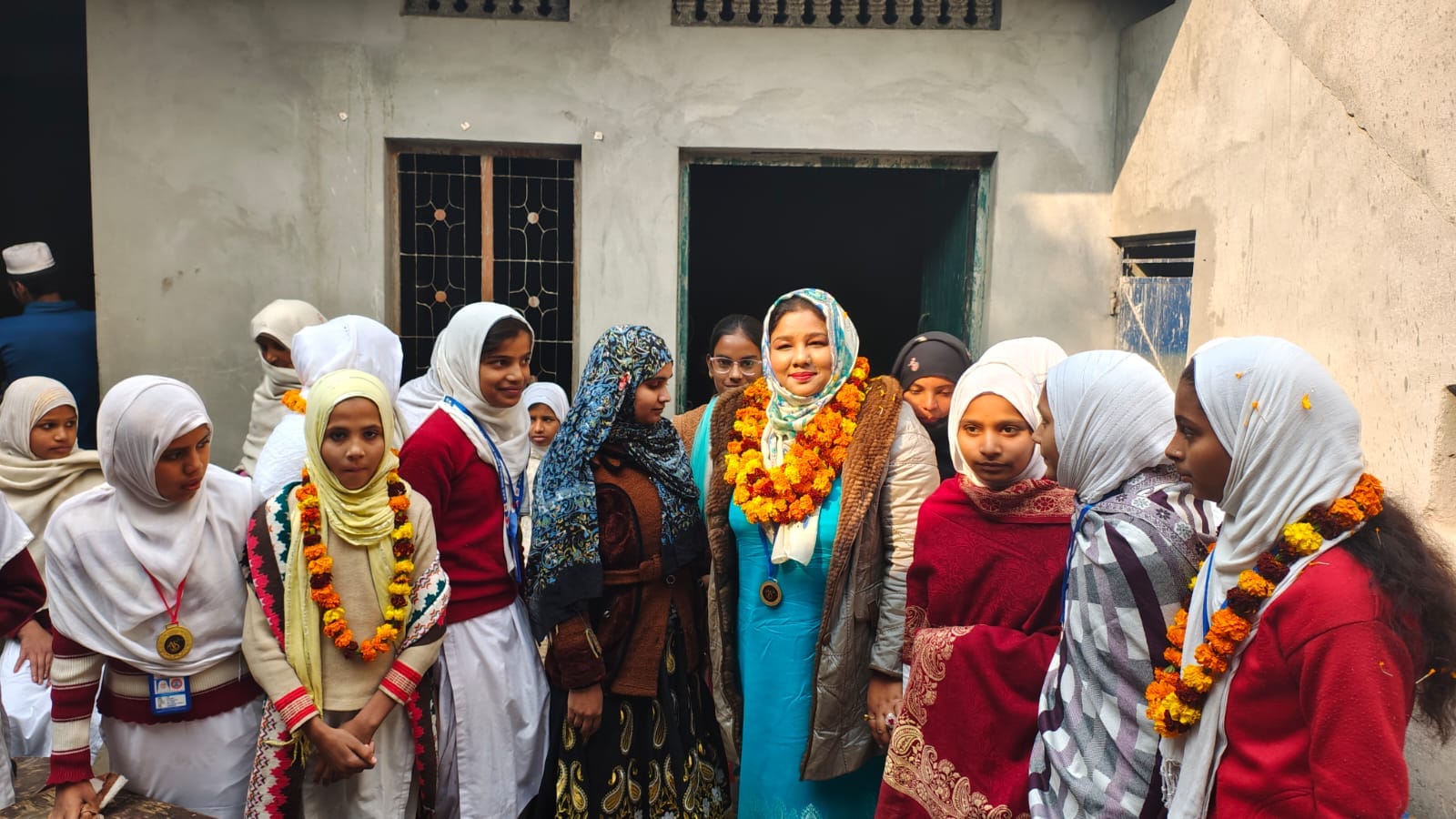 Village school girls wearing garlands and medals around Advocate Qazi