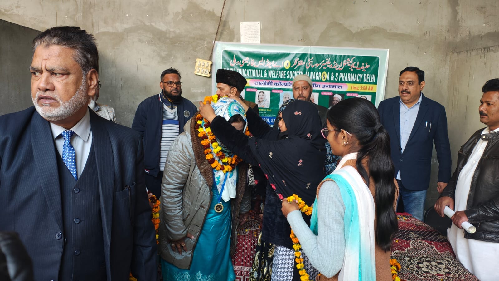 Ceremonial welcome with flower garlands before the Tawli educational conference banner
